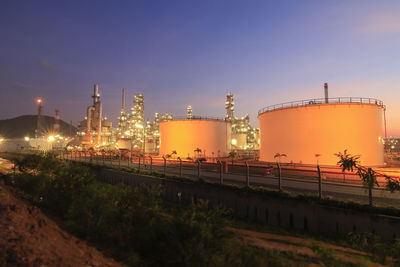 Illuminated factory against sky during sunset