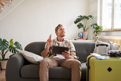 Young woman using mobile phone while sitting on sofa at home