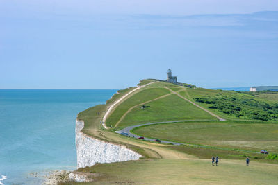 Scenic view of cliff by sea against blue sky during sunny day