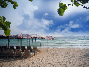 Chairs on beach against sky