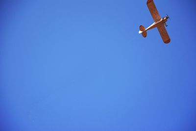 Low angle view of toy flying against clear blue sky