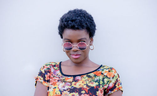 Portrait of smiling young woman standing against white wall