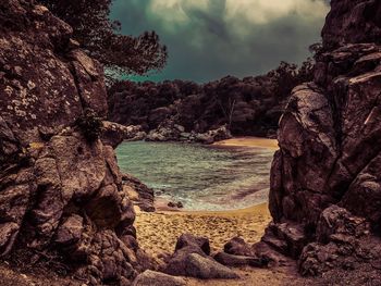 Rock formation on beach against sky