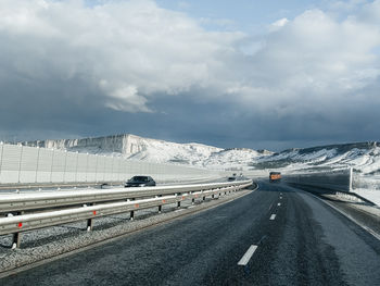 Road by snowcapped mountains against sky