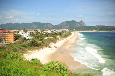 Scenic view of beach by mountains against sky