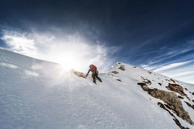 Man skiing on snowcapped mountain against sky