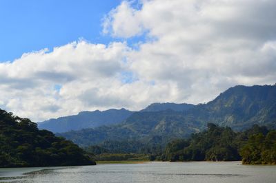 Scenic view of river by mountains against sky