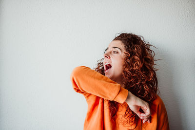 Mid adult woman coughing while standing against wall