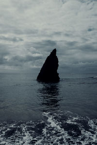 Silhouette rock in sea against sky