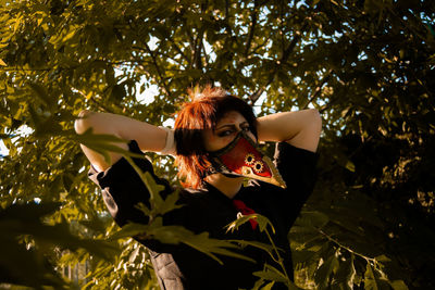 Portrait of woman with leaves against tree