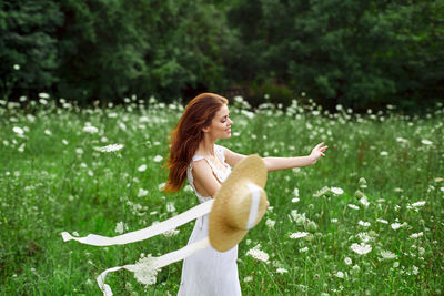 Young woman with arms raised on field