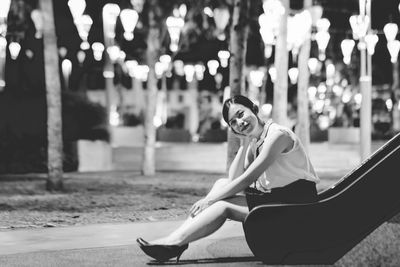 Portrait of smiling woman sitting on slide at park