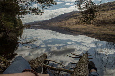 Low section of man on lake against sky