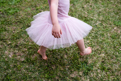 Low section of girl walking on field