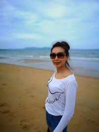 Portrait of woman standing at beach against sky