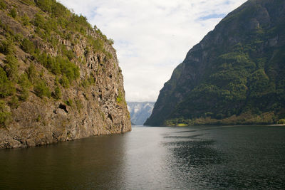 Scenic view of sea by mountains against sky