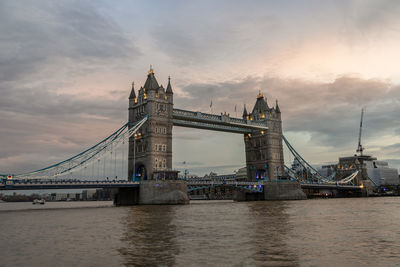 Suspension bridge over river against cloudy sky