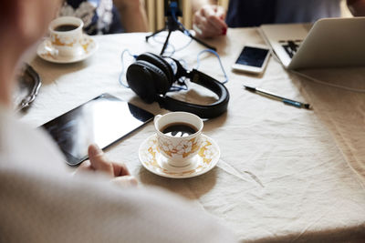 Cropped image of senior man having coffee while vlogging with friends at table