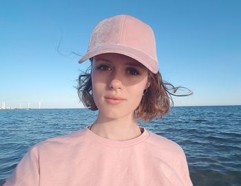 Portrait of young woman wearing cap against sea