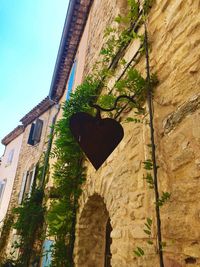 Low angle view of heart shape on wall against building