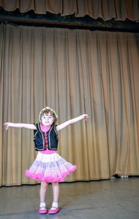 Happy girl performing against stage curtain