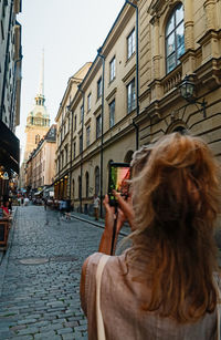 Rear view of woman photographing in city