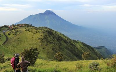 Panoramic view of people looking at mountains against sky