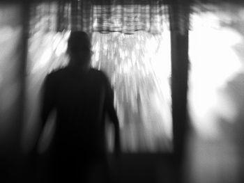 Rear view of silhouette woman standing against blurred background