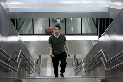 High angle view of young man with basketball moving up on steps
