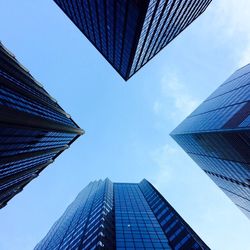 Directly below shot of modern buildings against blue sky