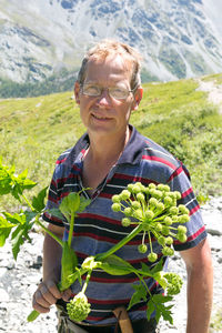 Portrait of smiling man holding branch standing outdoors
