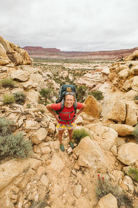 Female hiker with hands on hips looks at camera while hiking utah