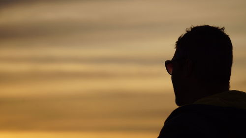Silhouette man wearing sunglasses against sky during sunset