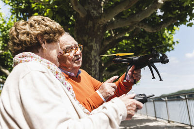 Senior couple playing with a drone in park