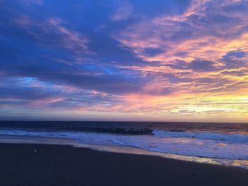 Scenic view of sea against dramatic sky during sunset