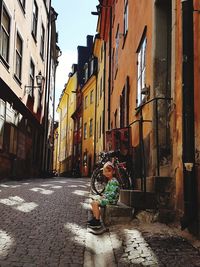 Woman on footpath amidst buildings in city