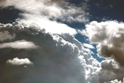 Low angle view of sunlight streaming through clouds