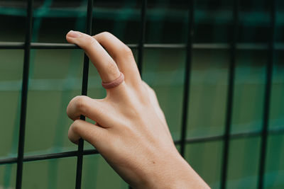 Close-up of person hand holding metal against wall