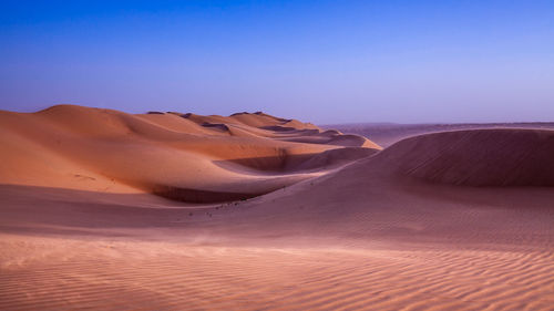 Scenic view of desert against clear blue sky