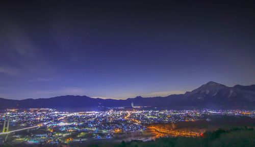 Illuminated cityscape against sky at night