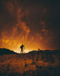 Silhouette man on land against sky during sunset