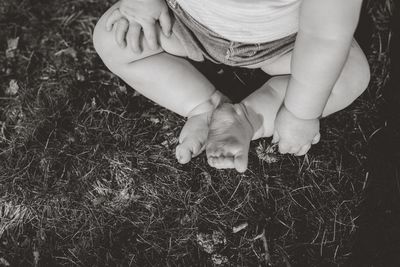 Low section of baby sitting on field