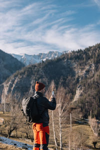 Rear view of man standing on mountain against sky