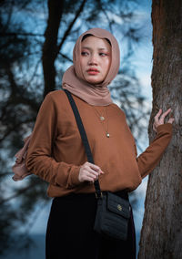 Thoughtful young woman wearing hijab standing outdoors