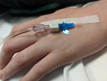 Cropped hand of patient wearing iv drip in hospital