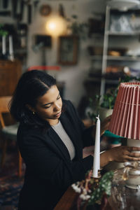 Young female owner arranging lamp while working at antique shop