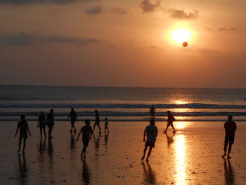 Silhouette people on beach against sky during sunset