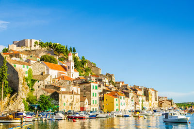 Residential buildings by sea against clear sky