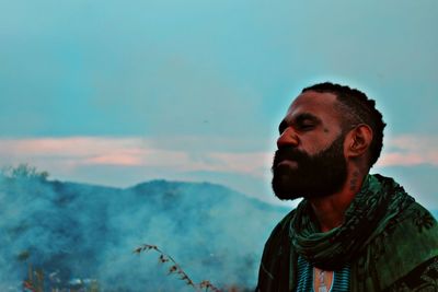 Portrait of young man looking away against sky