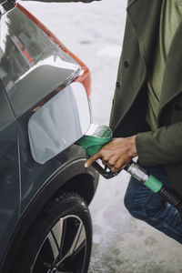 Midsection of man refueling car at fuel station